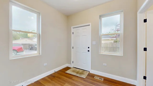 a view of an empty room with window and wooden floor