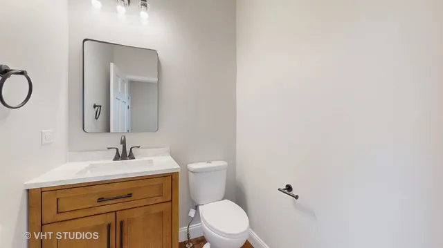 a bathroom with a toilet sink vanity and mirror