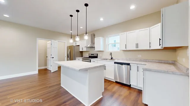 a kitchen with stainless steel appliances granite countertop a sink a stove a refrigerator and white cabinets with wooden floor