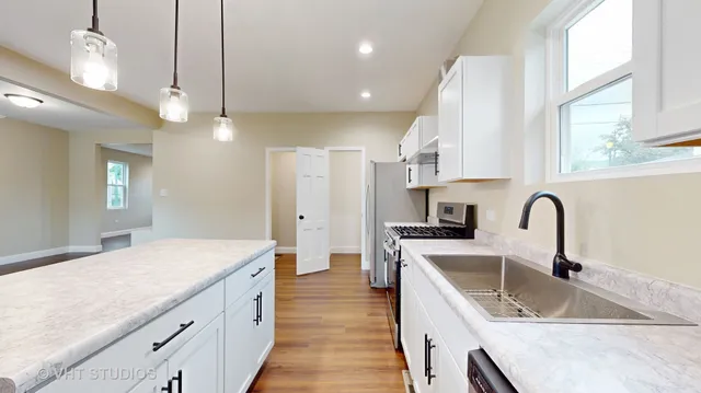 a kitchen with granite countertop a sink a counter space appliances and cabinets