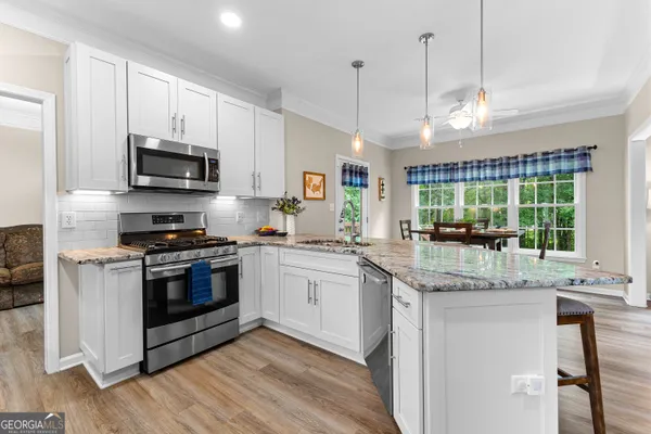 a kitchen with stainless steel appliances granite countertop a sink a stove a microwave and wooden cabinets