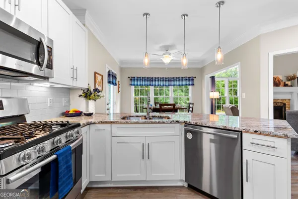 a kitchen with stainless steel appliances granite countertop a stove a refrigerator a microwave a dining table and chairs