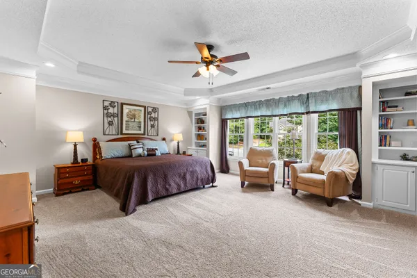 a spacious bedroom with a large bed and a chandelier fan