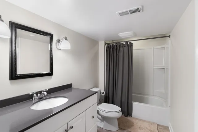 a bathroom with a granite countertop sink toilet a mirror a vanity and shower