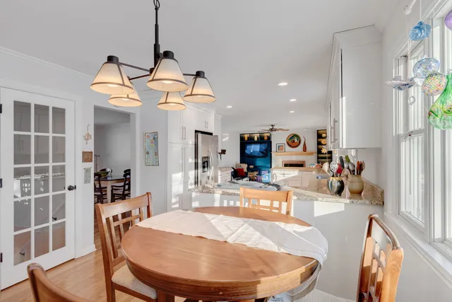 a dining room with wooden floor a chandelier a wooden table and chairs