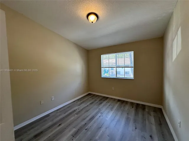 a view of a room that has wooden floor and a window