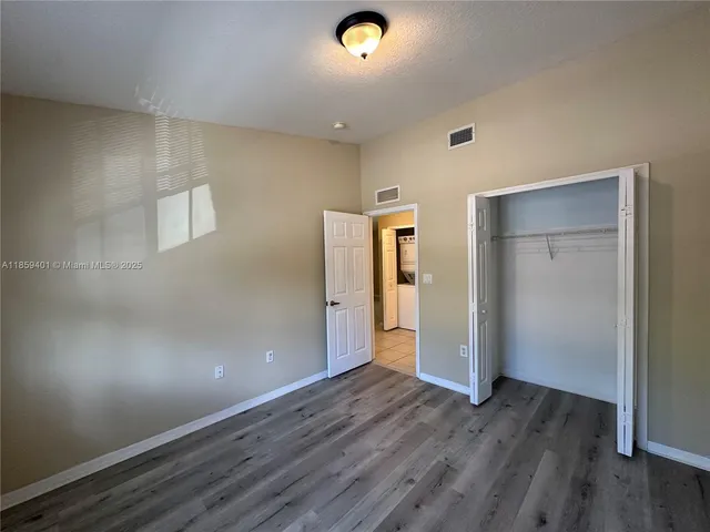 a view of an empty room with wooden floor and closet