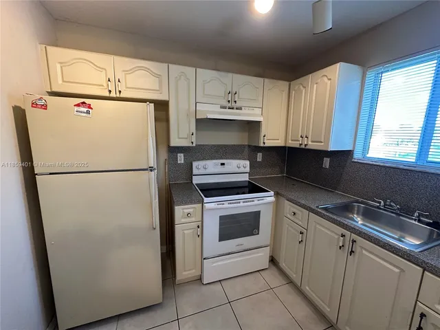 a kitchen with a refrigerator sink and cabinets