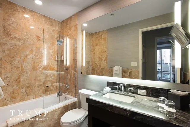 a bathroom with a granite countertop sink toilet a large mirror a bathtub and shower