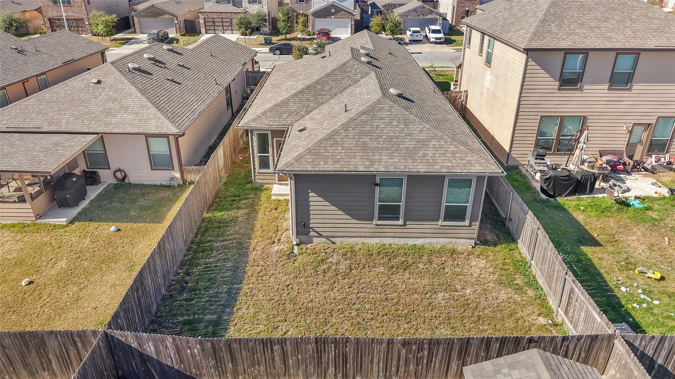 13917 Inaugural Street Manor, TX 78653 - Photo 19 of 39 Back of house featuring a shingled roof, a patio area, a fenced backyard, and a residential view