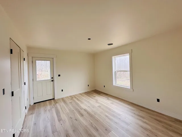 a view of an empty room with wooden floor and a window