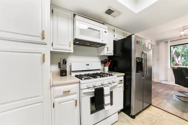 a kitchen with stainless steel appliances white cabinets and a refrigerator