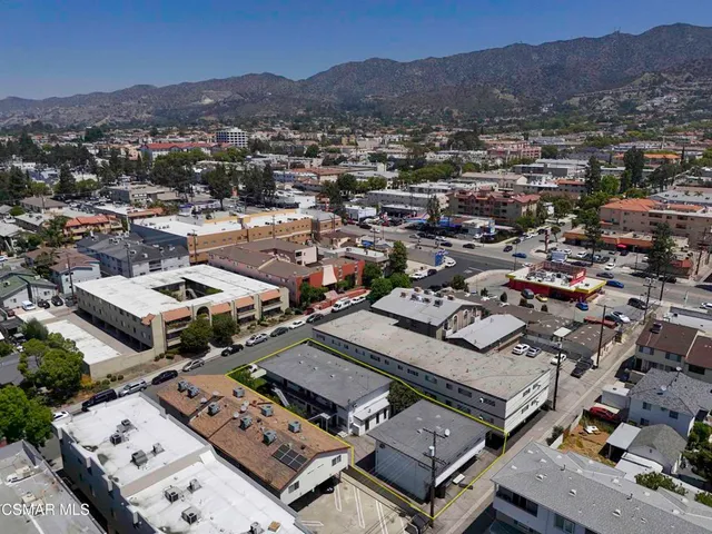 an aerial view of a city with lots of residential buildings and mountain view in back