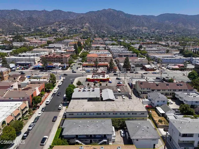 an aerial view of a city with lots of residential buildings and mountain view in back