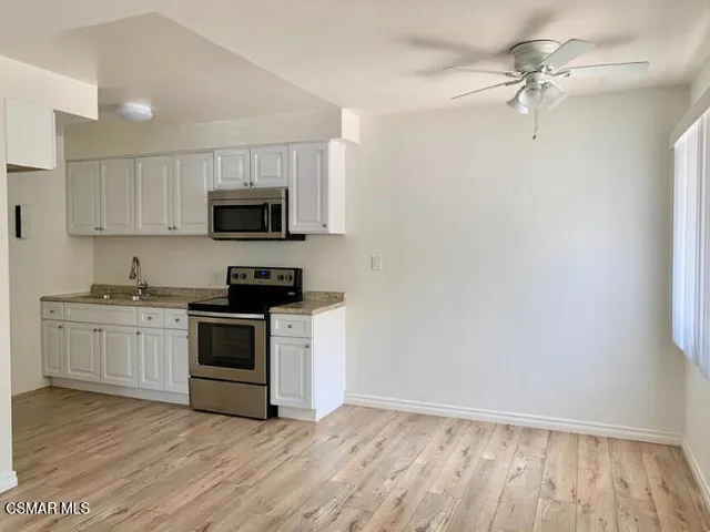 a kitchen with granite countertop a stove top oven a sink and dishwasher with white cabinets