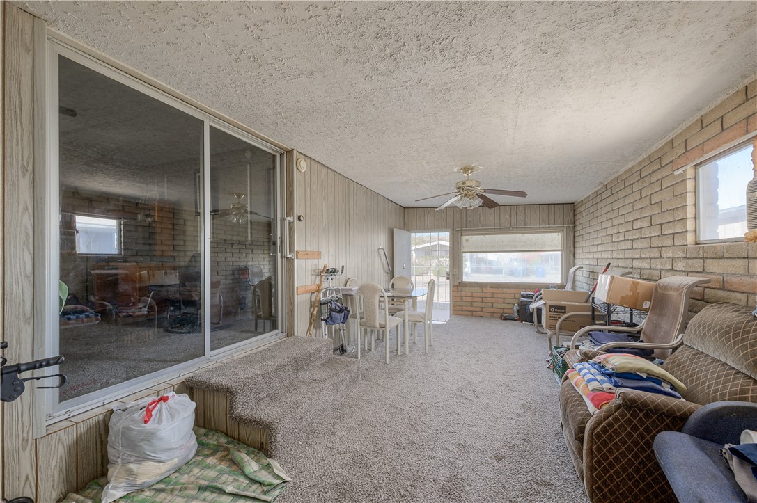 1798 Rio Grande Way Bullhead City, AZ 86442 - Photo 14 of 43 Living area featuring brick wall, carpet floors, a textured ceiling, and ceiling fan