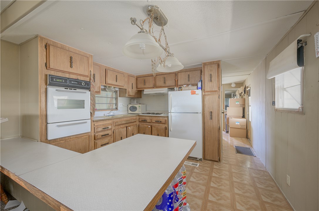 1798 Rio Grande Way Bullhead City, AZ 86442 - Photo 17 of 43 Kitchen with light countertops, a peninsula, white appliances, decorative light fixtures, and a warming drawer