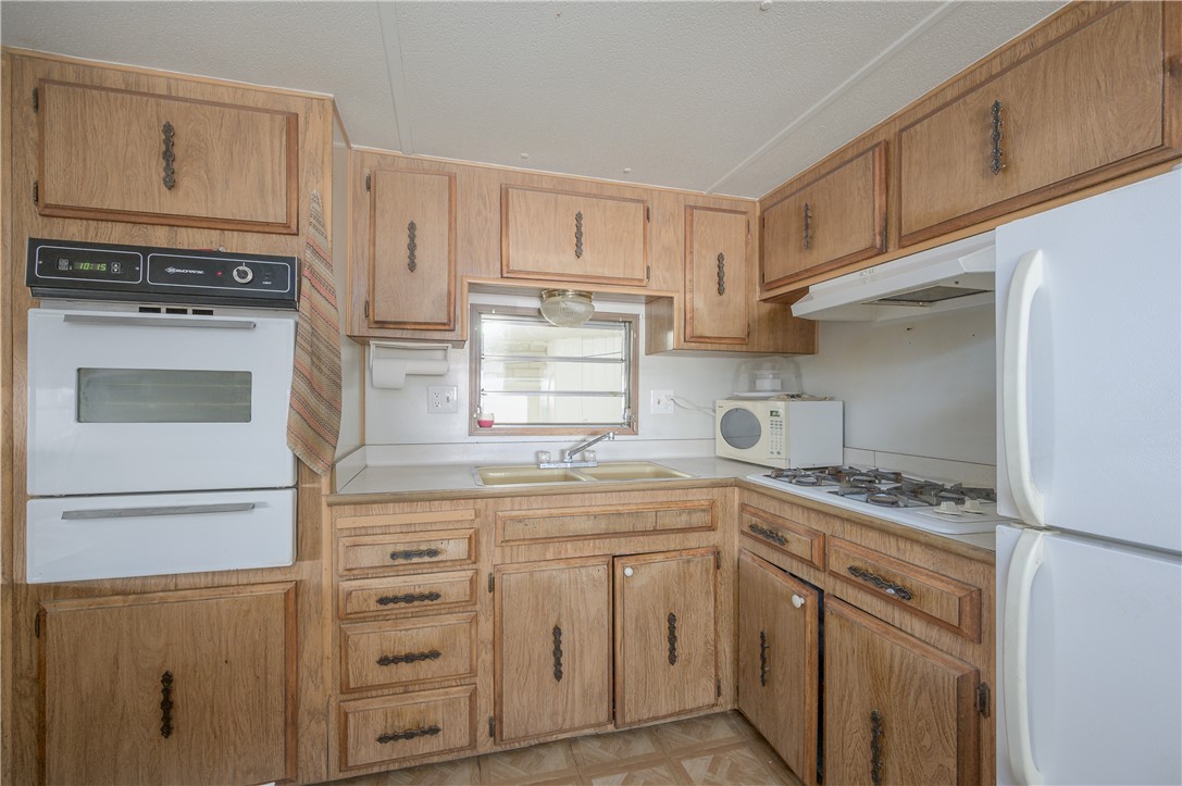 1798 Rio Grande Way Bullhead City, AZ 86442 - Photo 18 of 43 Kitchen with white appliances, under cabinet range hood, a warming drawer, and light countertops