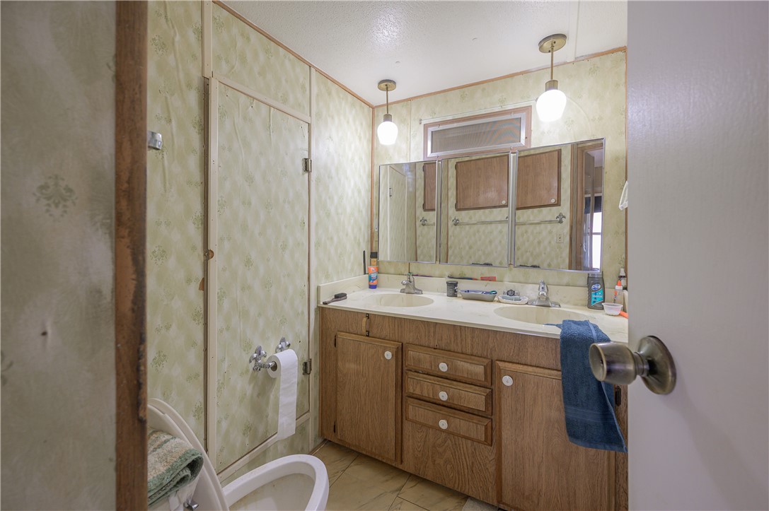 1798 Rio Grande Way Bullhead City, AZ 86442 - Photo 19 of 43 Bathroom featuring double vanity, wallpapered walls, crown molding, and a textured ceiling