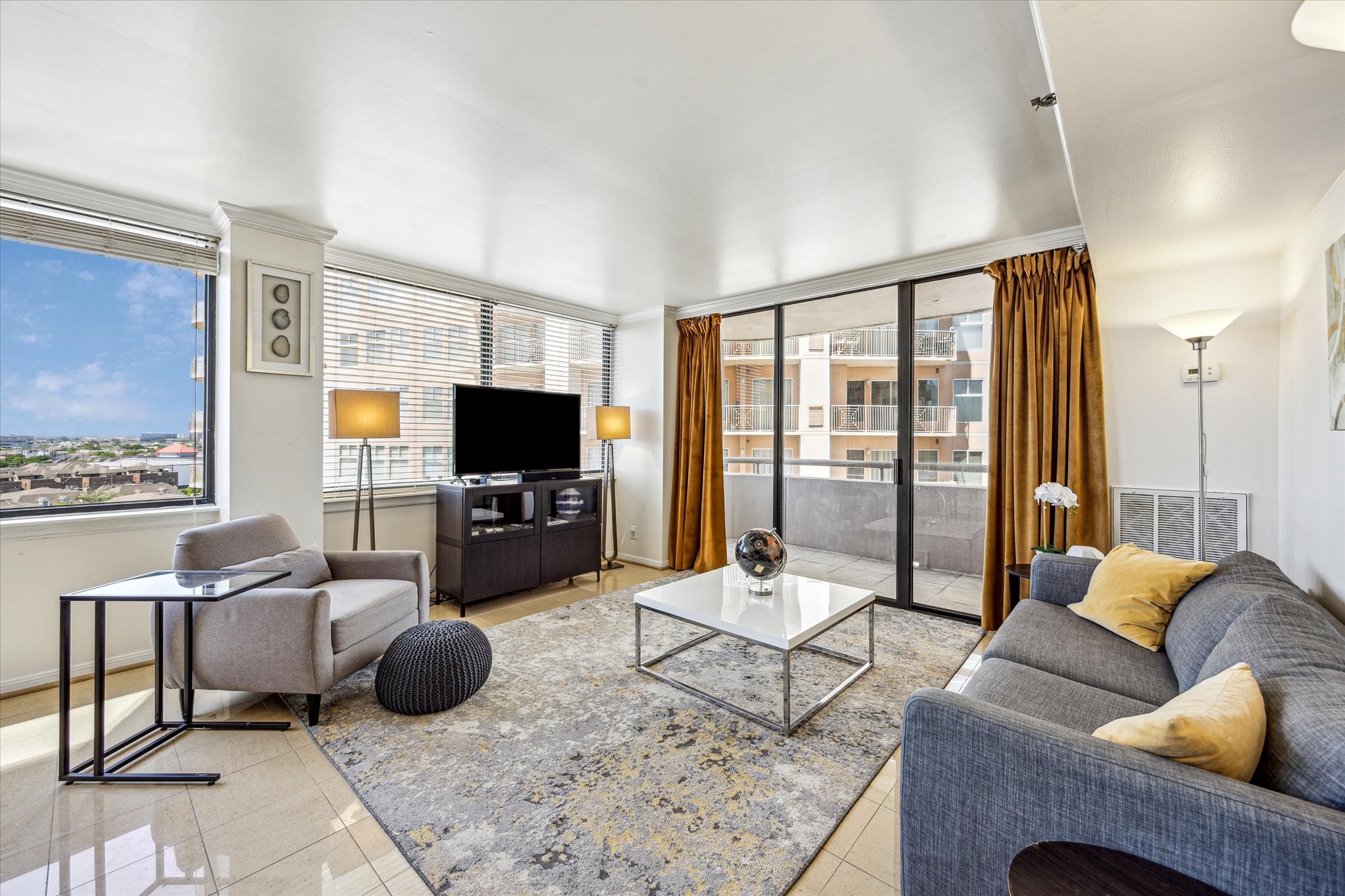 3525 Sage Road, Unit 1010 Houston, TX 77056 - Photo 1 of 34 The living room features expansive windows with blinds, sleek tile flooring, and direct access to the balcony.