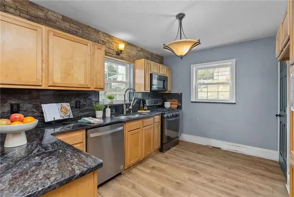 a kitchen with stainless steel appliances granite countertop a stove a sink and a microwave