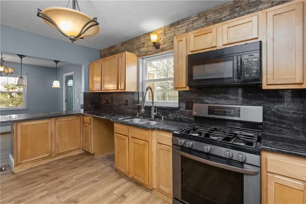 a kitchen with stainless steel appliances granite countertop a stove a sink and a microwave