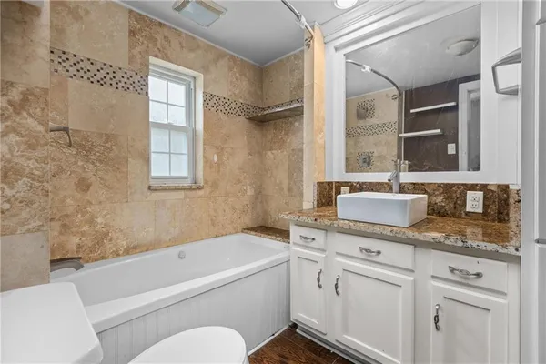 a bathroom with a granite countertop sink mirror bathtub and toilet