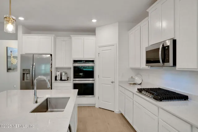 a large kitchen with stainless steel appliances kitchen island granite countertop a refrigerator a sink a stove a dining table and chairs