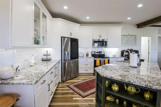 a kitchen with granite countertop kitchen island stainless steel appliances a stove refrigerator sink and cabinets