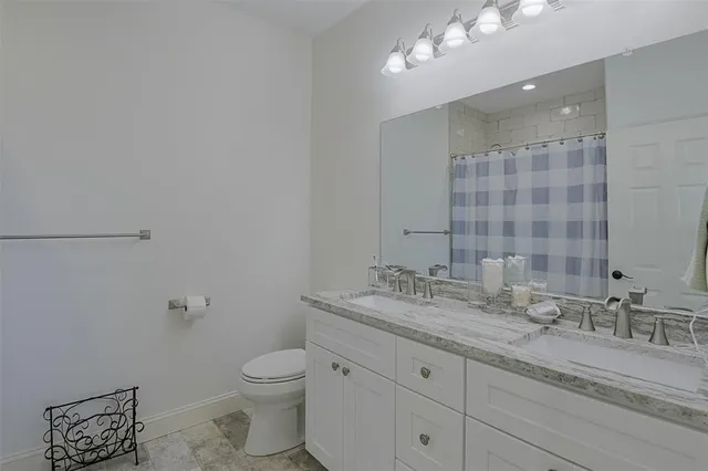a bathroom with a granite countertop sink a toilet and a mirror