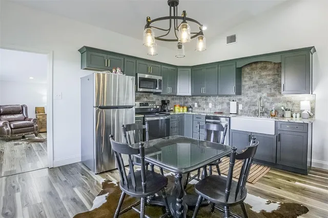 a kitchen with stainless steel appliances a dining table chairs refrigerator and cabinets