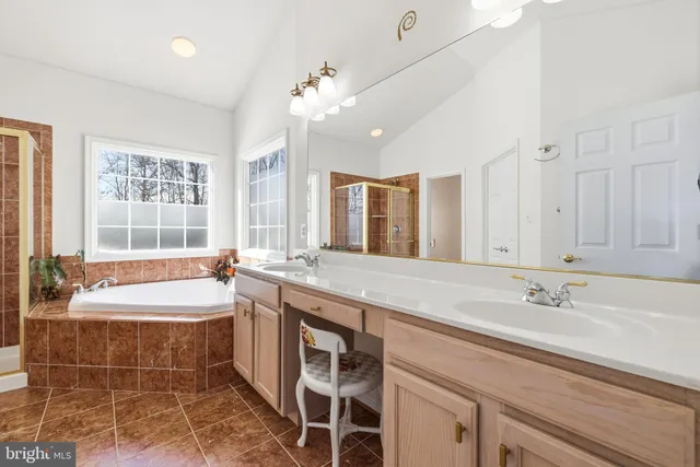 a bathroom with a tub a sink a mirror and a shower