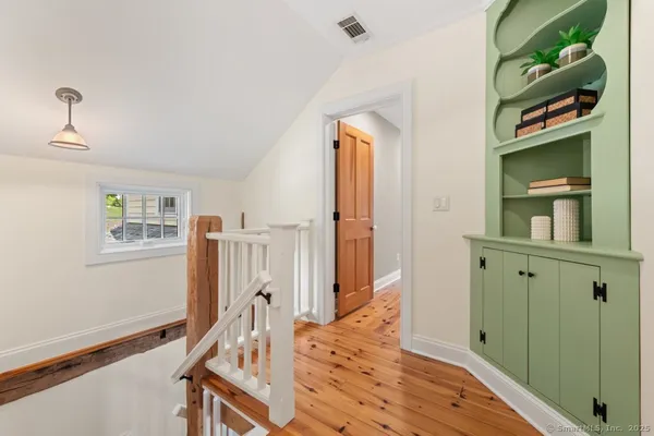 a view of a hallway with entryway and wooden floor