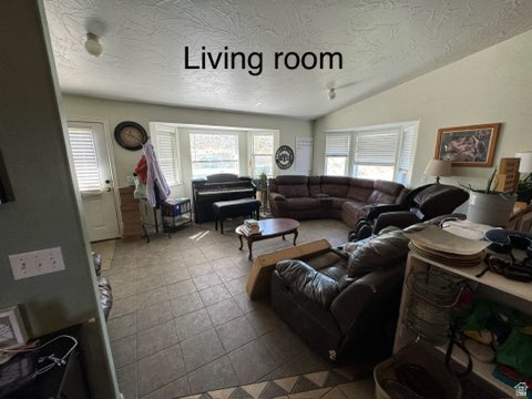 4355 Sagebrush Drive Enoch, UT 84721 - Photo 10 of 13 Living room featuring vaulted ceiling, tile patterned floors, and a textured ceiling