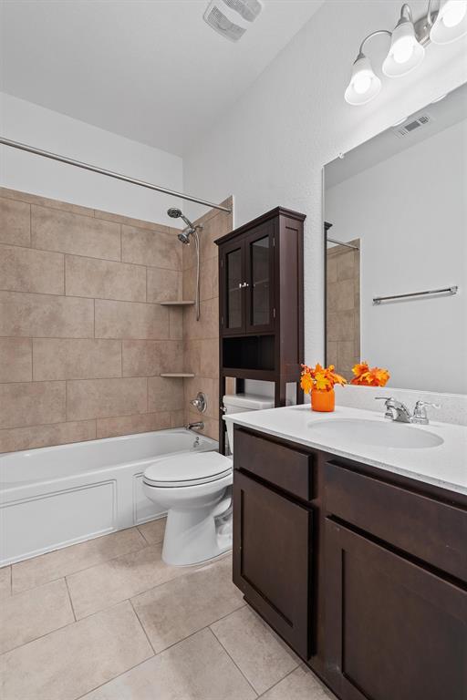 236 Prato Place Georgetown, TX 78628 - Photo 34 of 40 A well-appointed bath features a tiled shower surround and dark wood vanity with a pristine white countertop.