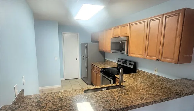 a kitchen with granite countertop a stove a sink and a microwave