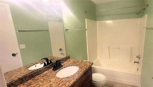 a bathroom with a granite countertop sink toilet a mirror and shower