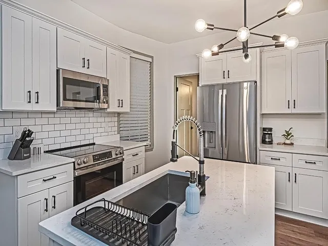 a kitchen with stainless steel appliances a stove a sink cabinets and a refrigerator