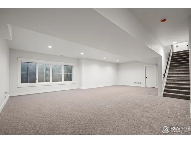 a view of an empty room with wooden floor and staircase