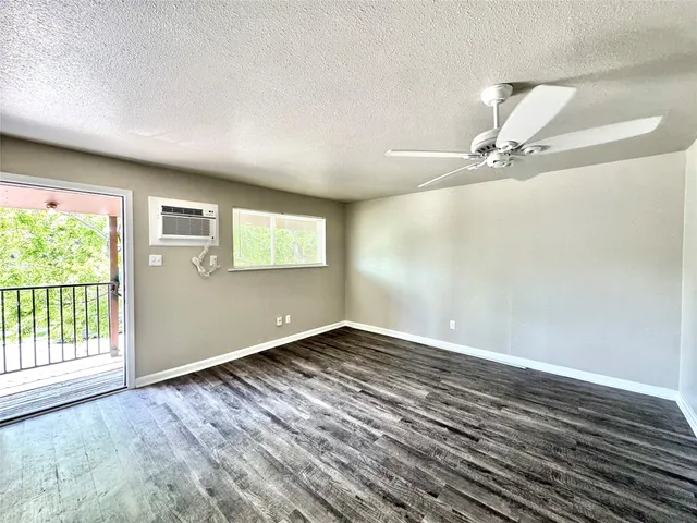 an empty room with wooden floor fan and windows