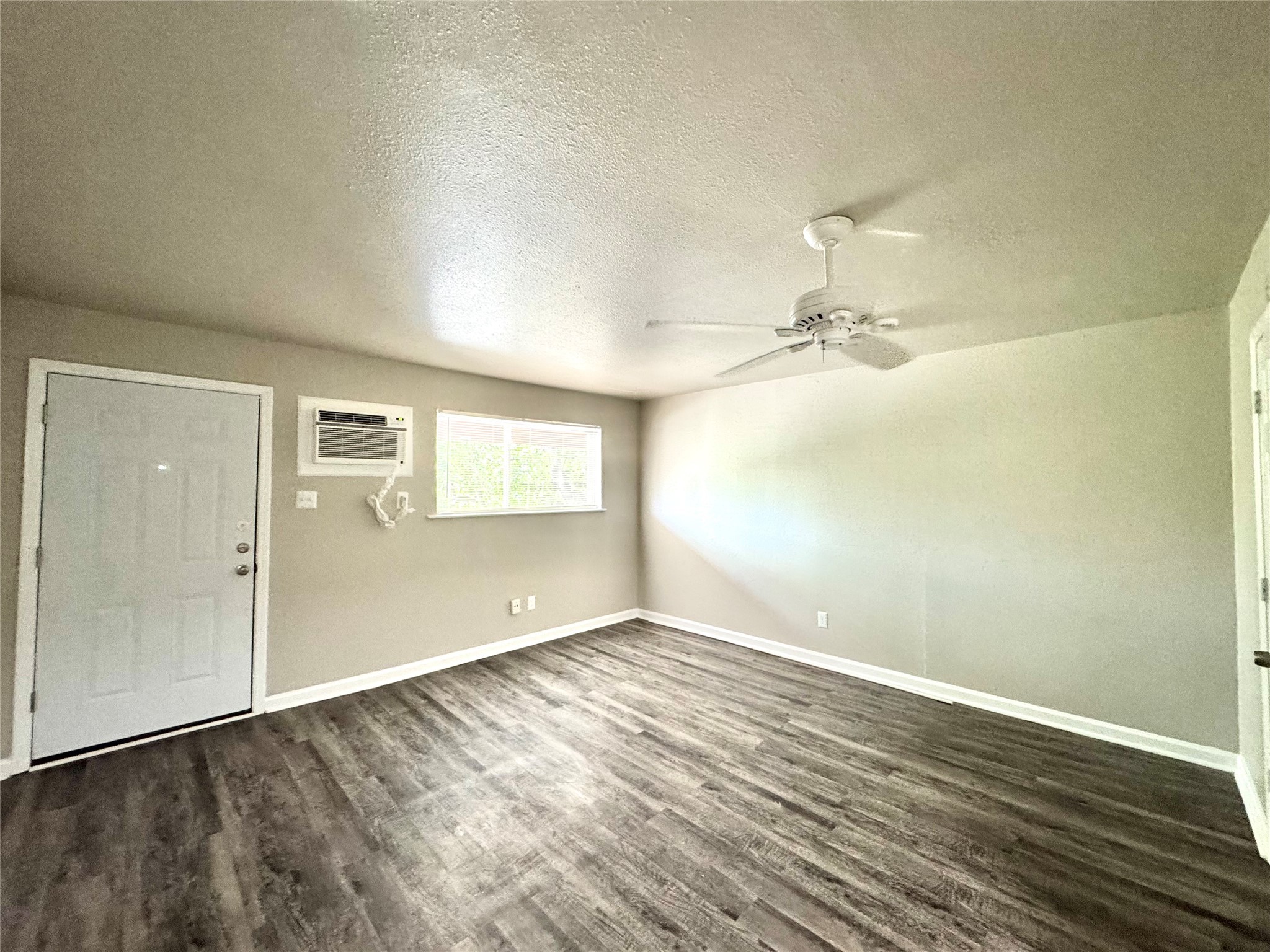 1756 West Main Street, Unit 22 Houston, TX 77098 - Photo 3 of 8 an empty room with wooden floor chandelier fan and windows