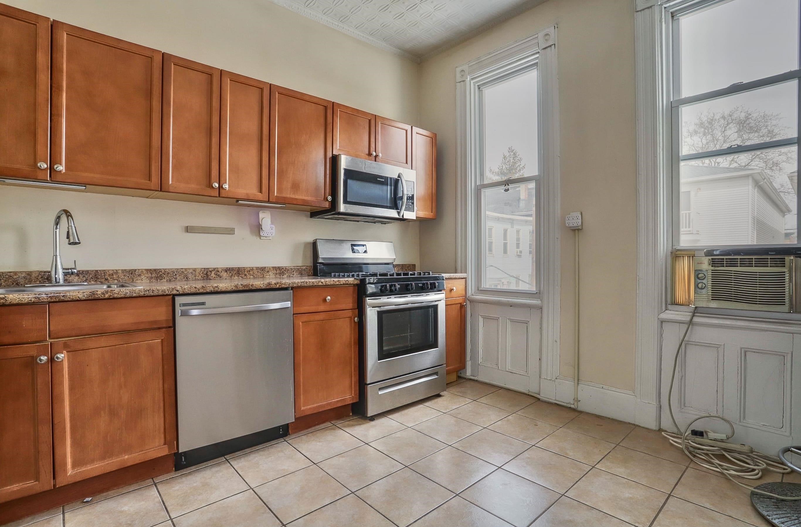 58 Prospect Street, Unit 2 Jersey City, NJ 07307 - Photo 7 of 26 a kitchen with granite countertop a stove top oven microwave and cabinets