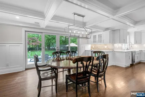 a kitchen with stainless steel appliances granite countertop a stove top oven a sink a dining table and chairs with wooden floor