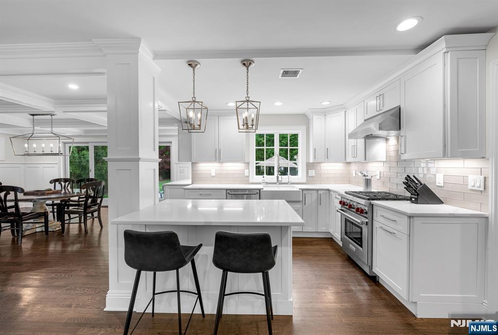 267 Merlin Place Wyckoff, NJ 07481 - Photo 19 of 49 a kitchen with stainless steel appliances granite countertop a stove top oven a sink a dining table and chairs with wooden floor