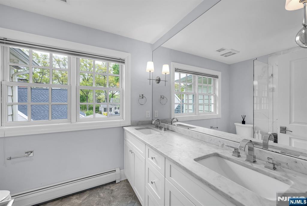 267 Merlin Place Wyckoff, NJ 07481 - Photo 30 of 49 a bathroom with double vanity sink a mirror and a bathtub