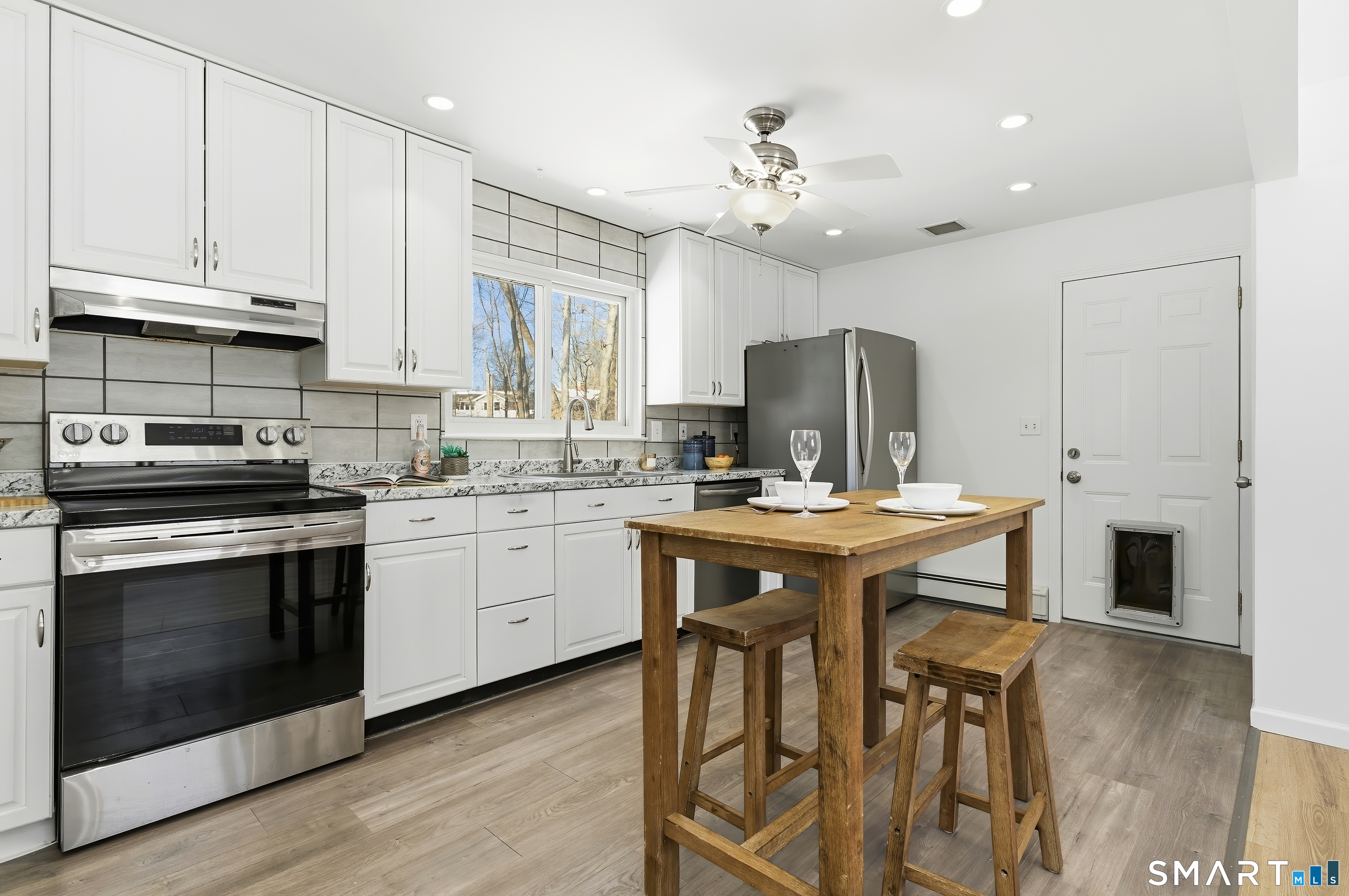 23 Ridgefield Road Wallingford, CT 06492 - Photo 11 of 28 a kitchen with kitchen island granite countertop a sink a stove a dining table and chairs