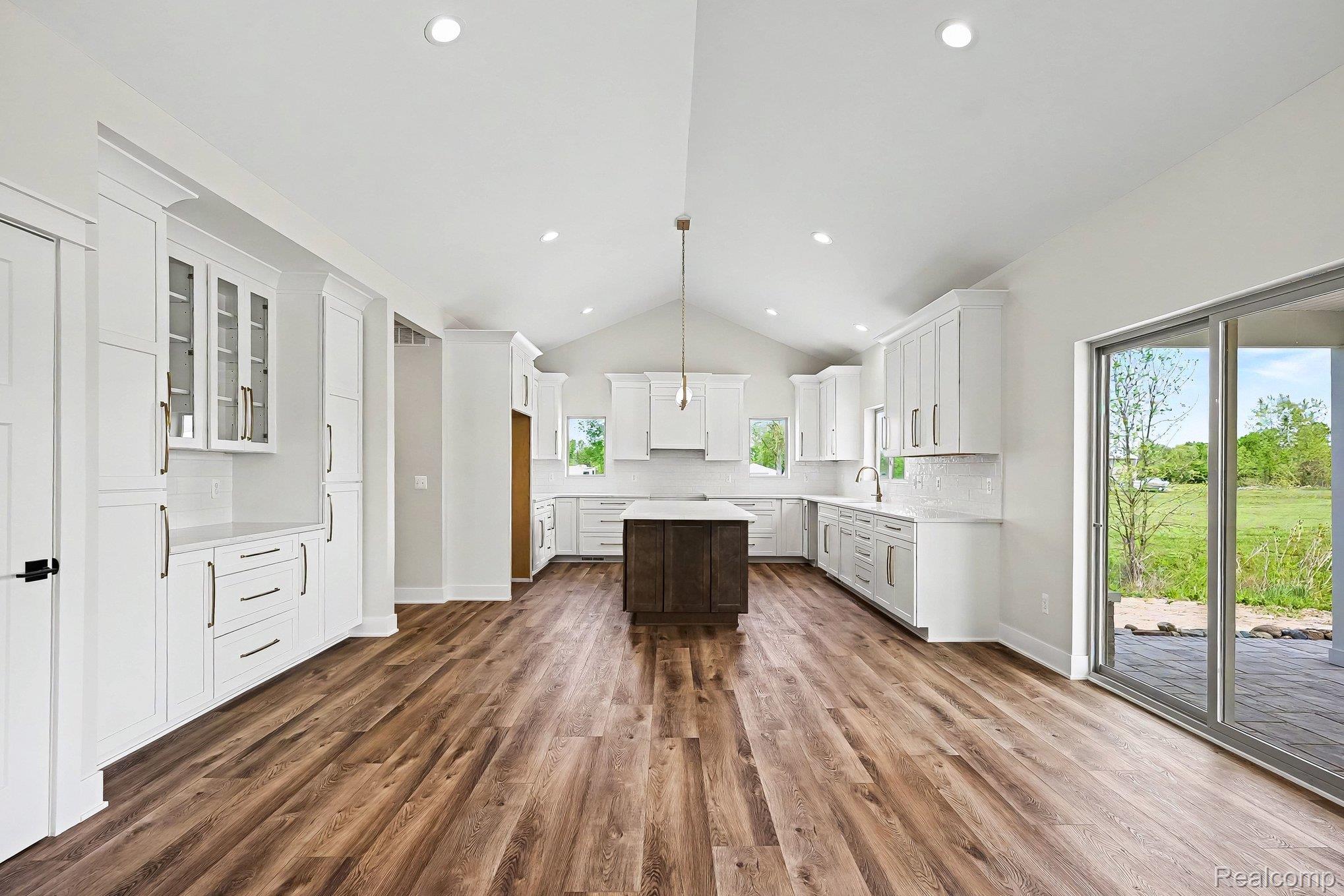 57560 Omo Road Ray, MI 48096 - Photo 11 of 44 Spacious kitchen featuring lvl flooring, white cabinetry, a central island with a contrasting finish, a vaulted ceiling, and recessed lighting