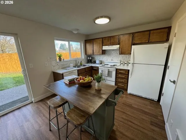 a kitchen with a table chairs a refrigerator and a stove top oven