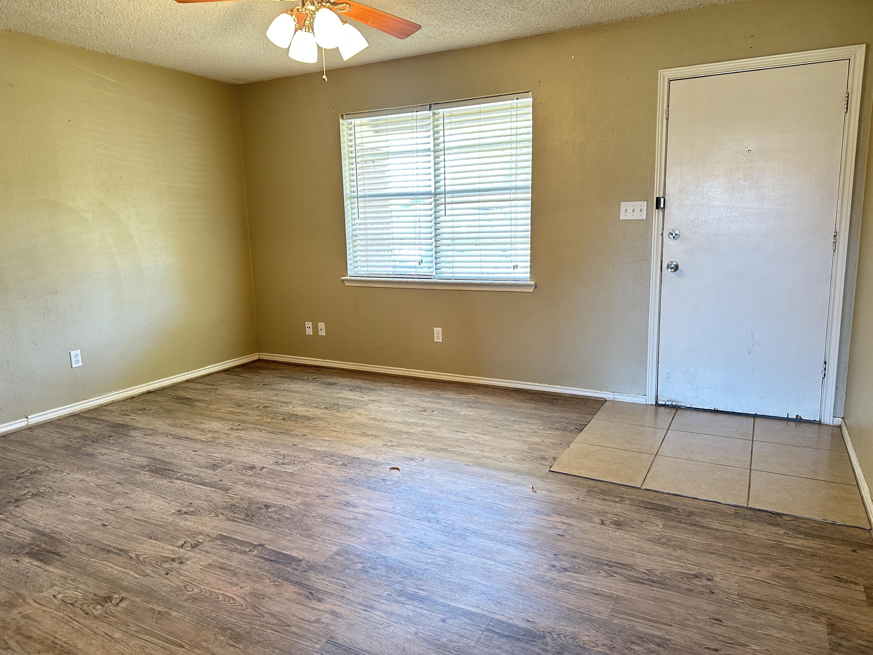 5613 16th Place Lubbock, TX 79416 - Photo 3 of 14 a view of an empty room with wooden floor and a window