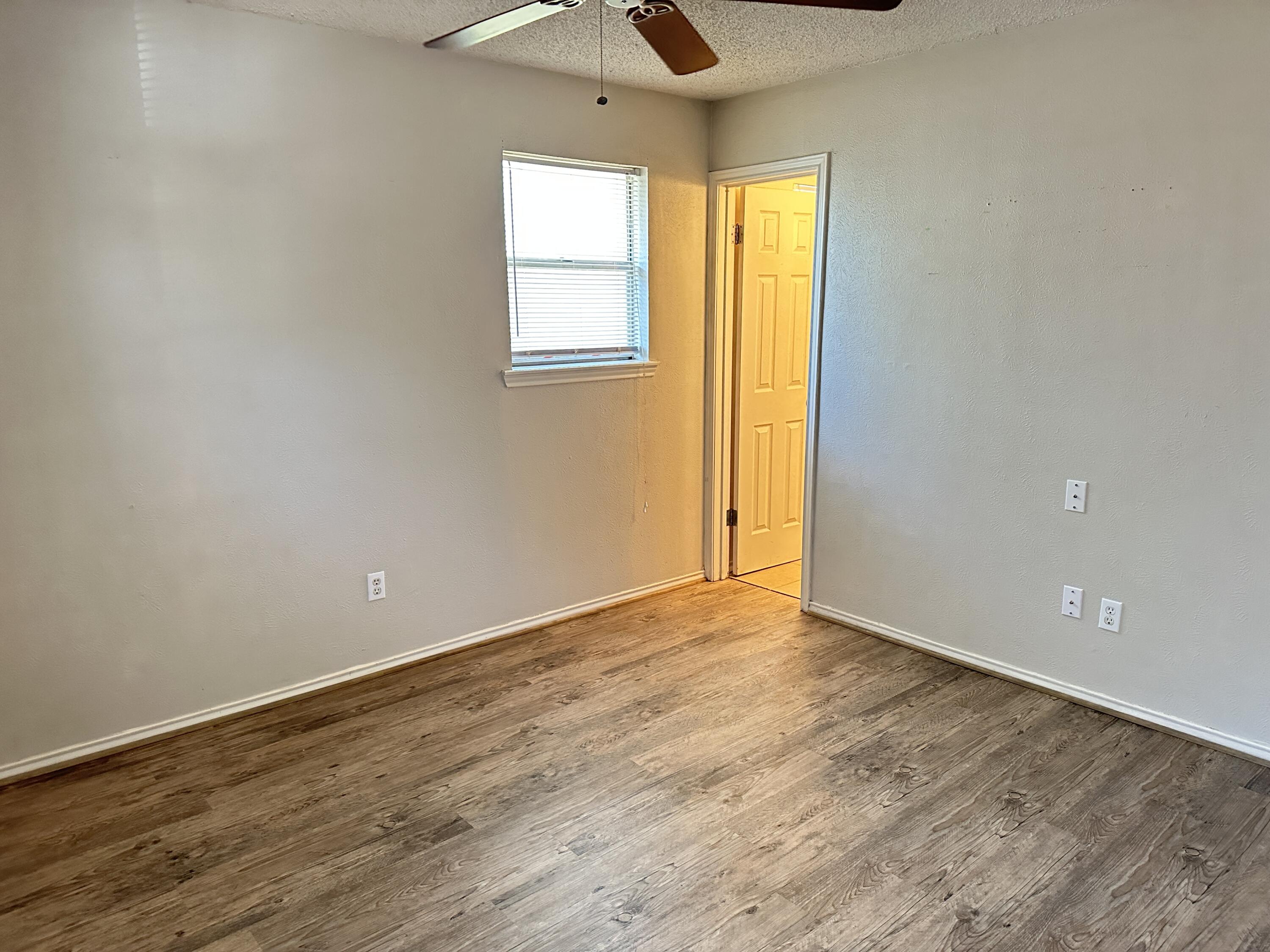 5613 16th Place Lubbock, TX 79416 - Photo 8 of 14 a view of an empty room with wooden floor and a window